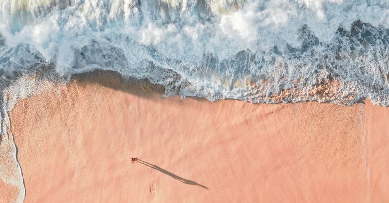 Beach Escape - Scenic Aerial Photo of a Sea Wave and Sandy Beach with Man Casting a Shadow