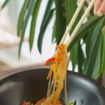 Pad Thai - Photo of Pad Thai Bowl and Hand Holding Chopsticks