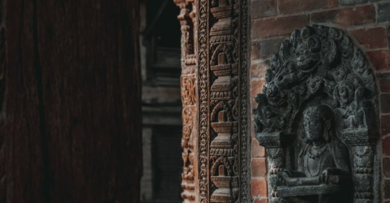 Temple Etiquette - A close up of a carved stone wall with a statue