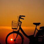 Bicycle Tour - Silhouette of Woman Using Camera in Front of City Bicycle