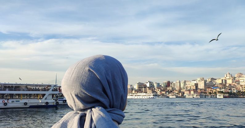 Skyline Views - A woman wearing a scarf looking out over the water