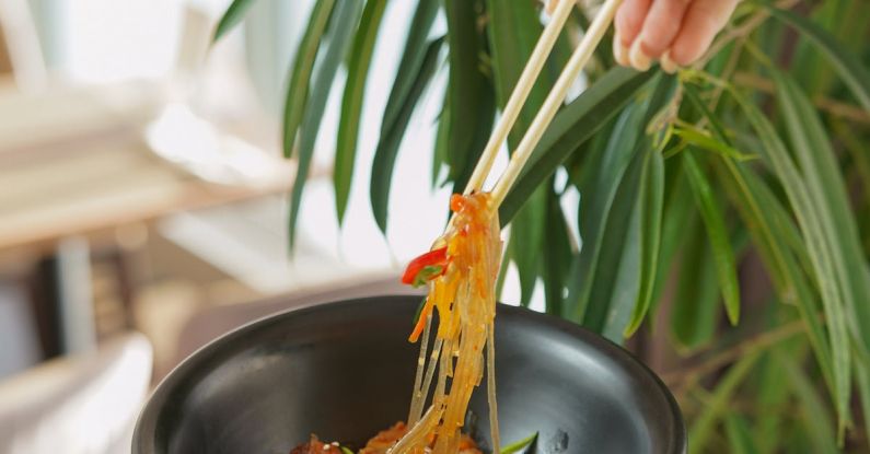 Pad Thai - Photo of Pad Thai Bowl and Hand Holding Chopsticks